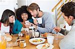 Friends sitting at a dining table and looking at a mobile phone