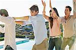 Group of friends dancing at the poolside