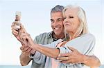 Couple taking a picture of themselves with a cell phone on the beach