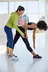 Female instructor assisting a woman in a gym