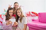 Three girls taking a picture of themselves with a mobile phone at a slumber party