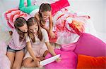 Three girls using a digital tablet at a slumber party