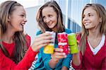 Close-up of three girls toasting with soft drink cans