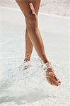 Woman splashing water with her feet on the beach