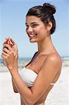 Beautiful woman holding a suntan lotion on the beach