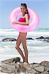 Beautiful woman standing with an inflatable ring on the beach