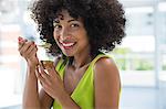 Portrait of a smiling woman eating kiwi fruit with a spoon