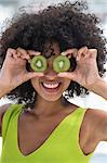 Woman holding kiwi fruits in front of her eyes