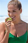 Smiling woman eating a green apple