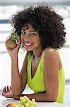 Portrait of a smiling woman showing kiwi fruits