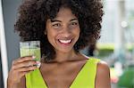 Portrait of a woman holding a glass of kiwi juice