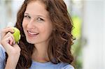 Portrait of a woman eating a green apple