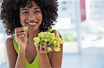 Portrait of a smiling woman eating grapes