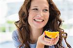 Close-up of a smiling woman holding a slice of an orange