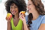 Close-up of two female friends eating fruits