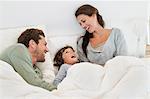 Parents playing with their son on the bed