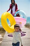 Children with their mother holding inflatable rings on a boardwalk on the beach