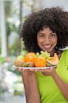 Portrait of a smiling woman holding a plate of fruits