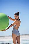 Beautiful woman holding a fitness ball on the beach