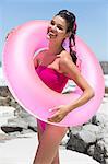 Beautiful woman standing with an inflatable ring on the beach