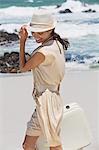 Beautiful woman carrying a suitcase on the beach