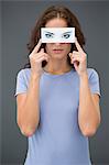 Woman holding a paper with false eyes in front of her face
