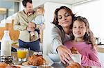 Girl having breakfast beside her mother at a kitchen counter