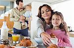 Girl having breakfast beside her mother at a kitchen counter