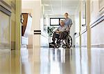 Nurse wheeling older patient in hospital