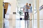 Nurse helping patient walk in hospital hallway