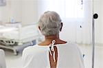 Older patient wearing gown in hospital room