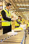 Workers checking packages on conveyor belt in warehouse