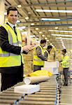 Workers checking packages on conveyor belt in warehouse