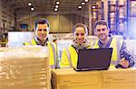 Workers using laptop in warehouse