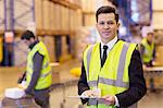 Businessman holding clipboard in warehouse