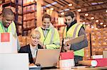 Businesswoman and workers using laptop in warehouse