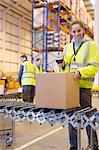 Worker scanning box on conveyor belt in warehouse