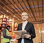 Businesswoman with folder and tablet computer in warehouse