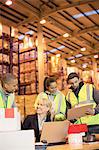 Businesswoman and workers talking in warehouse