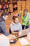 Workers using laptop in warehouse