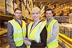 Businesswoman and workers smiling in warehouse