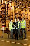 Businesswoman and workers smiling in warehouse