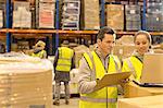 Workers using laptop in warehouse