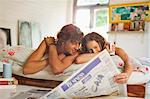 Couple reading newspaper together in bed