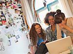 Women using laptop together in bedroom