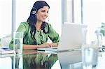 Businesswoman listening to headphones at desk