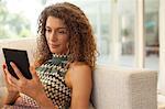 Woman using tablet computer on sofa