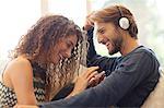 Couple listening to headphones on sofa