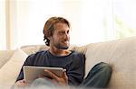 Man using tablet computer on sofa