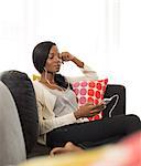 Woman listening to headphones on sofa